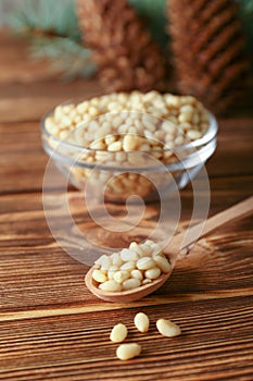 Cedar pine nuts in glass bowl with cones, oil, spoon cedar brunch on wooden background