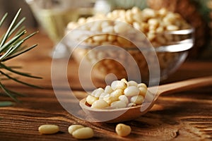 Cedar pine nuts in spoon with cones, oil, glass bowl, cedar brunch on wooden background