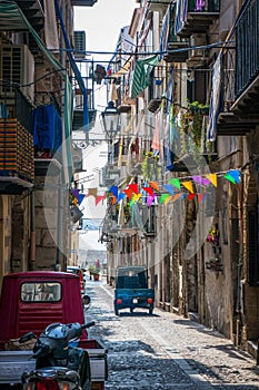 Cefalu old town narrow street view with cars parked and small balconies at the morning