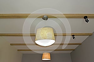 Ceiling chandeliers and laid on lamps on the wooden beams fixed on a ceiling