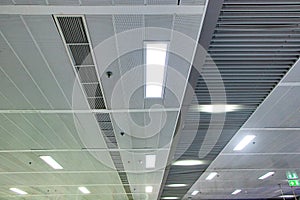 Ceiling with light bulbs lighting with ventilation pipes in train station in Thailand.