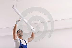 Ceiling light. Electrician installing led linear lamp indoors, low angle view. Space for text