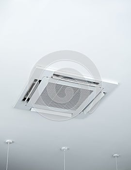 Ceiling mounted cassette type air conditioner decoration near ceiling lights on white building interior.