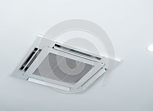 Ceiling mounted cassette type air conditioner decoration near ceiling lights on white building interior.