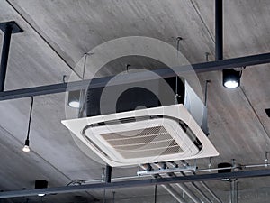 Ceiling mounted cassette type air conditioner decoration near the spot lights on the concrete construction building.