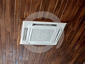 Ceiling mounted cassette type air conditioner system on wooden ceiling. White ceiling air conditioning.