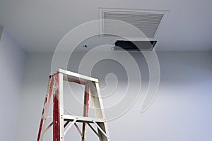 Ceiling panels hole in roof office from drain pipes leakage with step ladder.