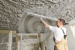 Plasterer smoothing plaster mortar on ceiling with screeder photo