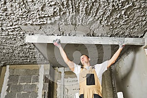 Plasterer smoothing plaster mortar on ceiling with screeder photo