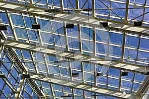 Ceiling structure made of metal and glass. Blue sky view