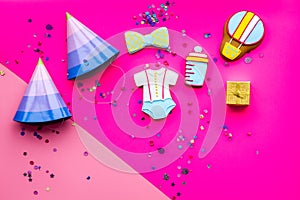 Celebrate child`s birthday. Cookies in shape of baby accesssories, party hats, gift box, confetti on pink background top