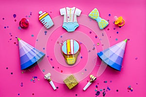 Celebrate child`s birthday. Cookies in shape of baby accesssories, party hats, gift box, confetti on pink background top