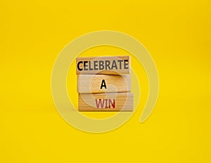 Celebrate a win symbol. Concept words Celebrate a win on wooden blocks. Beautiful yellow background. Business and Celebrate a win