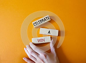 Celebrate a win symbol. Concept words Celebrate a win on wooden blocks. Businessman hand. Beautiful orange background. Business