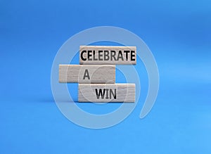 Celebrate a win symbol. Concept words Celebrate a win on wooden blocks. Beautiful blue background. Business and Celebrate a win