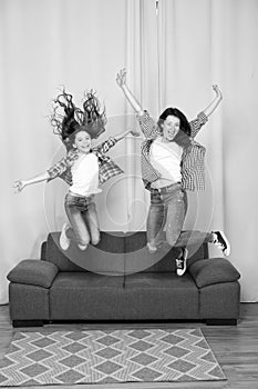 Celebrate womens day. Girls only. Mom and daughter friends. Mother cheerful daughter jumping couch. Happy childhood