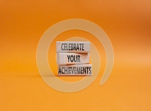 Celebrate your achievements symbol. Concept words Celebrate your achievements on wooden blocks. Beautiful orange background.