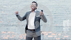 Celebrating business man cheering his promotion, success or achievement after reading a message on his phone while