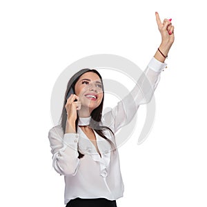 Celebrating businesswoman looking up and talking on the phone
