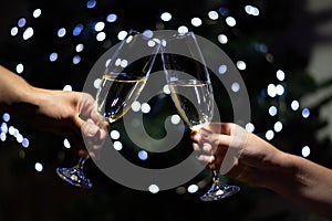 Celebrating Christmas at home, couple clinking glasses with champagne and holding sparklers on background of christmas tree