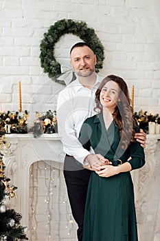 Celebrating Christmas together. Young couple in holiday clothes hugging near the Christmas tree. New Year, Valentine, love,