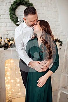 Celebrating Christmas together. Young couple in holiday clothes hugging near the Christmas tree. New Year, Valentine, love,
