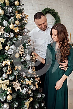 Celebrating Christmas together. Young couple in holiday clothes hugging near the Christmas tree. New Year, Valentine, love,