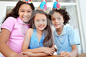 Celebrating a friends birthday. Portrait of three young children at a birthday party.
