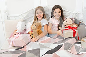 Celebrating the gift of together. Happy small children hold gift boxes. Adorable small girls with presents in bed