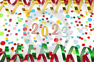 Celebrating New Year 2023, paper streamers and confetti on white background.