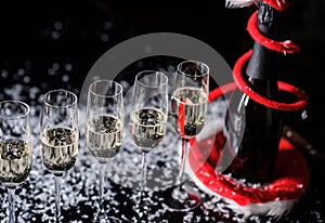 Celebrating new year, birthday, xmas party. Bottle of champagne in a bucket on black backgroud. Santa's hat