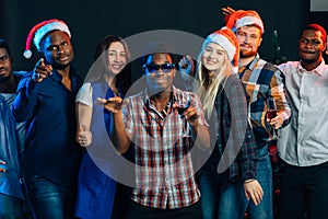 Celebrating New Year together. Group of beautiful young people in Santa hats