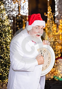 Celebrating New Year. wait for xmas presents. santa man hold alarm clock. new year midnight. clock showing almost