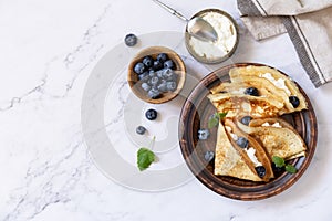 Celebrating Pancake day, healthy breakfast. Delicious homemade crepes with blueberries and ricota on a stone tabletop. Top view photo