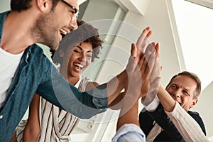 Celebrating success. Business people giving each other high-five and smiling while working together in the modern office