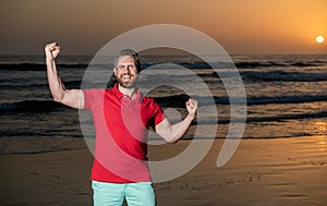 celebrating success. copy space. happy man with beard in sunset over sea. successful guy