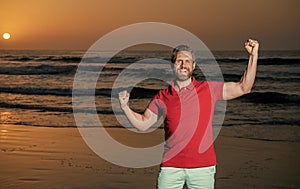 celebrating success. copy space. happy man with beard in sunset over sea. successful guy