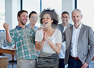 Celebrating their business success. a group of happy coworkers celebrating standing in an office.