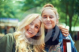 Celebrating their friendship. Two young women standing together with a bottle of wine at an outdoor festival.