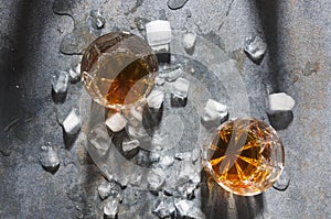 Celebration at the bar.Pair of glasses with alcohol drinks and ice cubes, top view. Glasses with whisky served in the unusual way