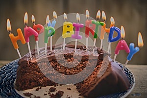 Celebration chocolate cake half eaten with lit candles