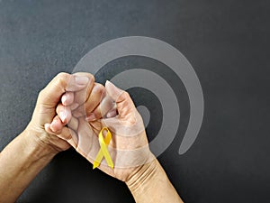 Celebration Day Concept - yellow ribbon on palm background. Symbolize the world suicide prevention day. Stock photo.