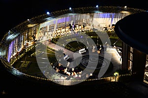 Celebration, function site is beautifully illuminated with strings of golden lights. fountain, landscape Night time.