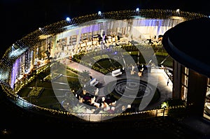 Celebration, function site is beautifully illuminated with strings of golden lights. fountain, landscape Night time.