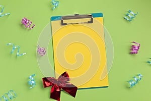 Celebration planning concept. Clipboard, bow, serpentine, on green background