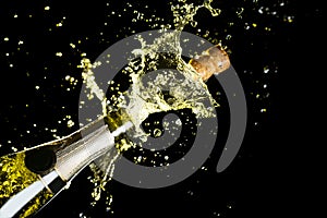 Celebration theme with explosion of splashing champagne sparkling wine on black background. photo