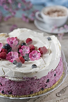Celebratory cake with berries and a cup of aromatic coffee. Vintage napkin, spoon and pink flowers