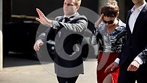 Celebrity bodyguards protecting actress from annoying photojournalist outdoors