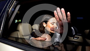 Celebrity couple in car hiding with hand from magazine photographers cameras