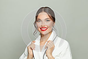 Celebrity woman with makeup in white bathrobe smiling on white background